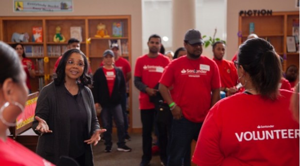 African american woman talking to a diverse group of Santander Consumer employees in red volunteer shirts