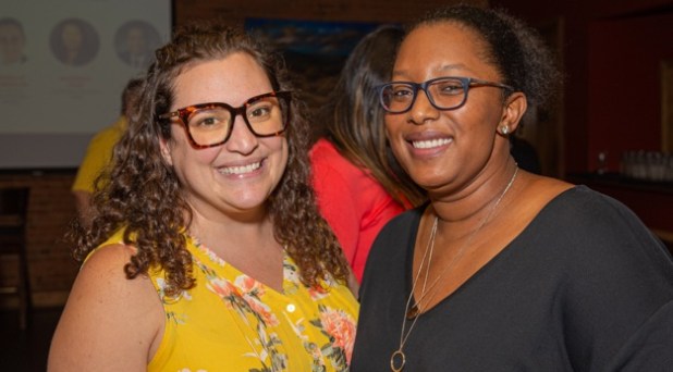 A white woman and african american woman both wearing glasses and smiling